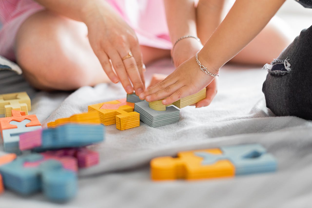 Hands of children and adults assembling colorful wooden puzzle blocks together.